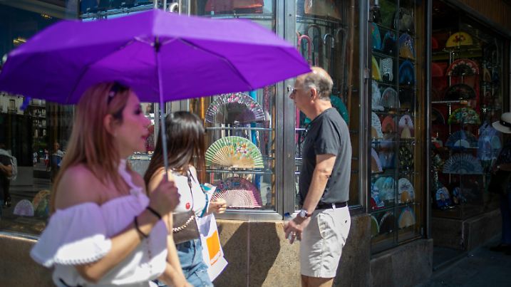 Daily life in Madrid, Spain - 20 Jul 2024 A woman carries a sunshade as she passes outside a fan shop on a street in the center of Madrid during the first heat wave in the Spanish capital. Madrid Spain Copyright: xDavidxCanalesx/xSOPAxImagesx dccslormsdrid240720-19
