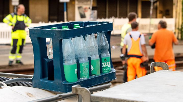 ARCHIV - 20.07.2022, Bremen: Ein Kasten mit Wasserflaschen steht auf einer Baustelle, auf der Bauarbeiter bei hohen Temperaturen an Straßenbahn-Gleisen arbeiten. (zu dpa: «Arbeiten bei übermäßiger Hitze: Zahl der Betroffenen steigt») Foto: Sina Schuldt/dpa +++ dpa-Bildfunk +++