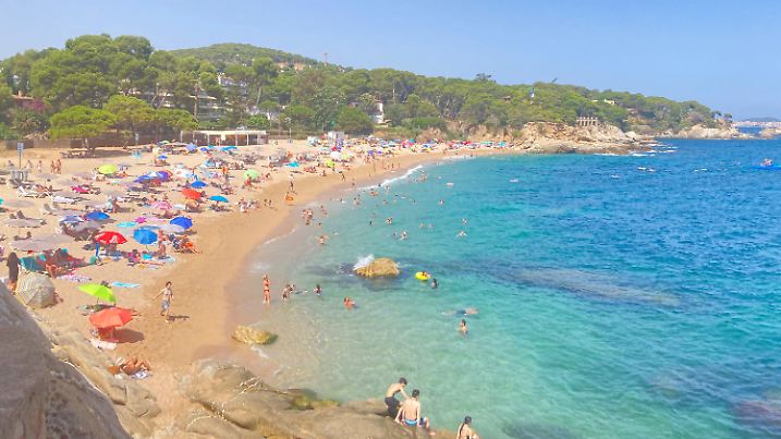ARCHIV - 29.07.2024, Spanien, Platja D'Aro: Badegäste liegen in einer der vielen Buchten am Strand. Vielerorts auf der Welt schwinden Strände, auch in Spanien. (zu dpa: ««Der Strand ist weg» - Spaniens Küsten leiden») Foto: Emilio Rappold/dpa +++ dpa-Bildfunk +++