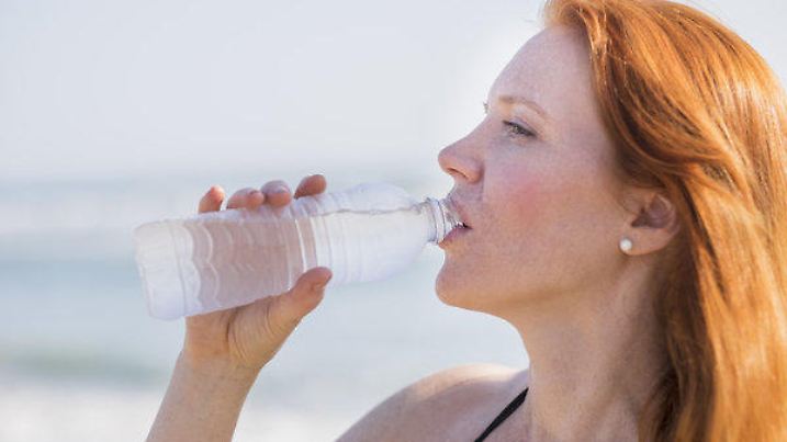 View of woman drinking water on beach, Ansicht von Frau mit Trinkwasser am Strand Keine Weitergabe an Drittverwerter.