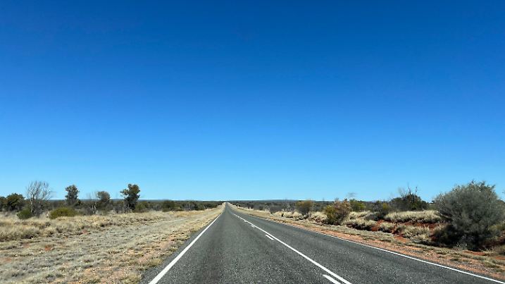 06.08.2024, Australien, Alice Springs: Eine Straße wenige Kilometer von Alice Springs führt direkt in abgelegene Outback-Regionen. Die Entfernungen sind in dieser Region riesig. Für viele Kinder sind die Wege zu weit, um eine Schule zu besuchen. Deshalb gibt die School of the Air Fernunterricht für Kinder im Outback. In Alice Springs gab es die erste School of the Air, sie wurde 1951 eröffnet. Mittlerweile gibt es sie an 17 Standorten. (zu dpa: «School of the Air: Wie Kinder in Australiens Outback lernen») Foto: Carola Frentzen/dpa +++ dpa-Bildfunk +++