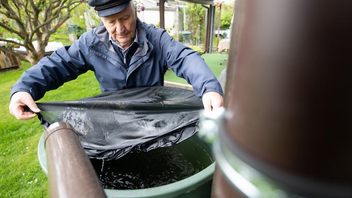 Detelf Beetz legt während der Vorstellung des Pilotprojekts «Tigermückenpopulation in Treptow-Köpenick» in der Kleingartenanlage Grüne Weide ein Netz über einer Wassertonne, um zu Verhindern, dass sich Tigermücken dort vermehren können. Das Pilotprojekt ist Bestandteil des Maßnahmenplans zur Abwehr der invasiven Tigermücke in Berlin.