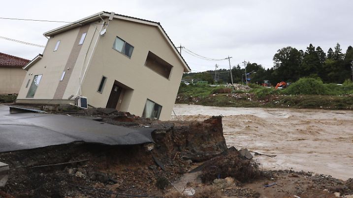 22.09.2024, Japan, Suzu: Ein Wohnhaus neigt sich dem Ufer eines angeschwollenen Flusses zu nach heftigen Regenfällen. Foto: ---/kyodo/dpa +++ dpa-Bildfunk +++