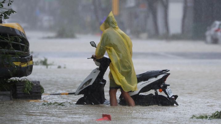 A man pushes a motorbike through a flooded road as Typhoon Krathon makes landfall in Kaohsiung, southern Taiwan, Thursday, Oct. 3, 2024. (AP Photo/Chiang Ying-ying)