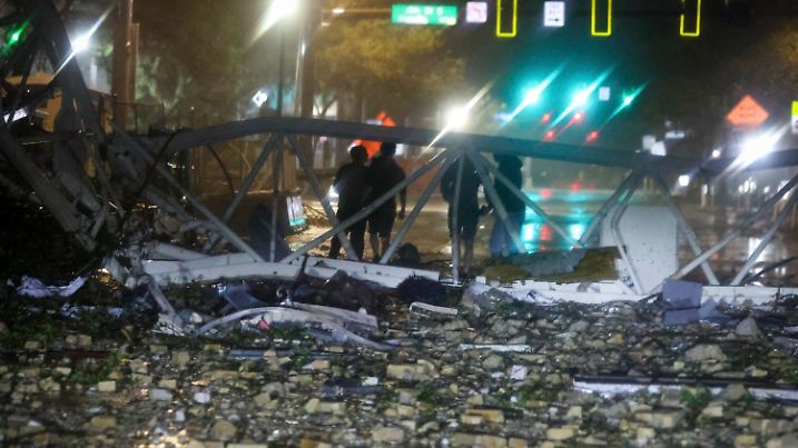 A group is silhouetted against a fallen crane along 1st Avenue South near the Tampa Bay Times offices in St. Petersburg, Florida, Thursday, Oct. 10, 2024, as Hurricane Milton's strong winds tore through the area. (Chris Urso/Tampa Bay Times via AP)