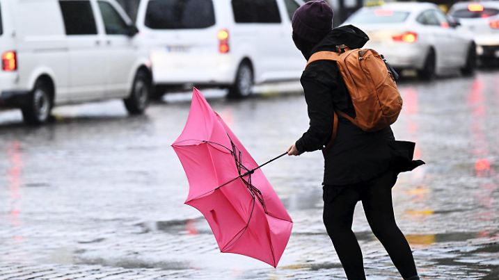 11.10.2023, Finnland, Helsinki: Eine Frau kämpft mit ihrem Regenschirm, der von einer Windböe bei Regen erfasst wird. Foto: Vesa Moilanen/Lehtikuva/dpa +++ dpa-Bildfunk +++