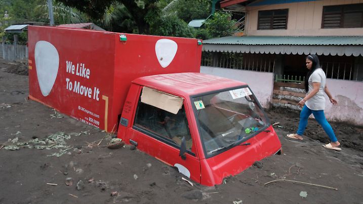 A resident walks beside a van buried by volcanic mud that flowed down from Mayon volcano after heavy rains caused by Tropical Storm Trami hit Guinobatan town, Albay province, Philippines on Wednesday Oct. 23, 2024. (AP Photo/John Michael Magdasoc)
