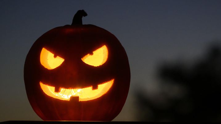 28.10.2024, Schweiz, Daillens: Als Halloween-Dekoration steht ein ausgehöhlter, beleuchteter Kürbis mit einem geschnitzten grinsenden Gesicht in einem Garten in Daillens, Schweiz. Halloween ist ein Fest, das am 31. Oktober gefeiert wird, bei dem sich die Menschen verkleiden, Kürbisse schnitzen, Partys feiern und Kinder um Süßes oder Saures bitten. Foto: Laurent Gillieron/KEYSTONE/dpa +++ dpa-Bildfunk +++