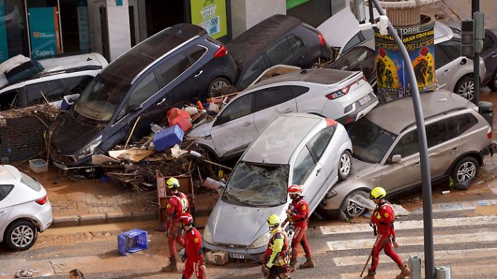 30.10.2024, Spanien, Valencia: Rettungskräfte gehen an aufgestapelten Autos vorbei, die von den Überschwemmungen weggeschwemmt wurden. Foto: Alberto Saiz/AP +++ dpa-Bildfunk +++
