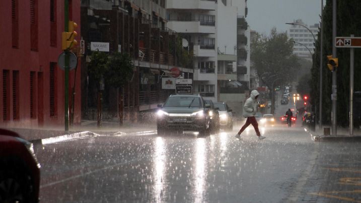 01.11.2024, Spanien, Palma: Ein Passant läuft während eines Regenschauers in Palma über die Straße. Auch die Balearen erwarten Unwetter auf den beliebten Touristeninseln Mallorca und Menorca. Bisher gilt dort die zweithöchste Warnstufe Orange. Foto: Clara Margais/dpa +++ dpa-Bildfunk +++