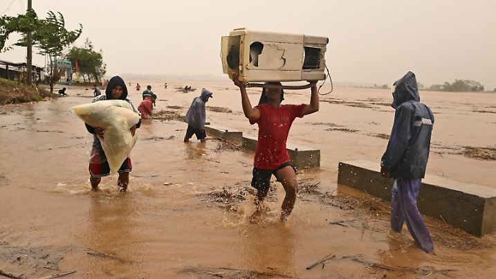 Residents carry their belongings as the river swells, following heavy rains from Typhoon Toraji in Ilagan City, Isabela province, northern Philippines on Monday, Nov. 11, 2024. (AP Photo/Noel Celis)