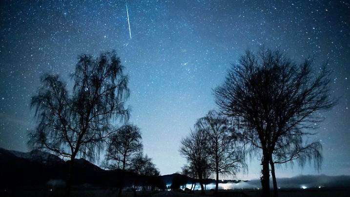 ARCHIV - 14.12.2020, Bayern, Kochel Am See: Eine Sternschnuppe ist während des Geminiden-Meteteorstroms über der Staatsstraße 2062 zu sehen. (zu dpa: «Sonne, Mond und Sterne im Dezember - längste Nacht des Jahres») Foto: Matthias Balk/dpa +++ dpa-Bildfunk +++