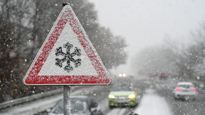 21.11.2024, Niedersachsen, Leer: Ein Verkehrschild an der Südring-Brücke warnt vor Gefahr von Schnee- oder Eisglätte auf der Fahrbahn, während Schnee fällt. Foto: Lars Penning/dpa +++ dpa-Bildfunk +++