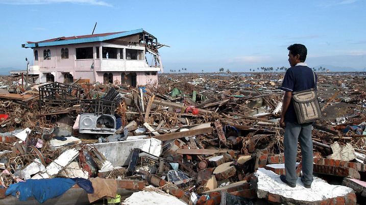 ARCHIV - Alexander Julkarnaen, 39, steht zwischen den Trümmern seines Hauses und Heimatortes in Banda Aceh (Archivfoto vom 09.01.2005). Bei der furchtbaren Tsunami-Katastrophe von  2004 kommen am zweiten Weihnachtstag mehr als 230.000 Menschen ums Leben. Gewaltige Flutwellen verwüsten innerhalb weniger Stunden die Küsten des Indischen Ozeans. Auslöser ist ein schweres Erdbeben der Stärke 9,1 vor der Küste der indonesischen Insel Sumatra. Mindestens 1,5 Millionen Menschen werden obdachlos. Foto: EPA/ANDY RAIN  (zu dpa-Paket: "Chronologie der Flutkatastrophe in Südasien 2004" vom 16.12.2009)  +++(c) dpa - Bildfunk+++
