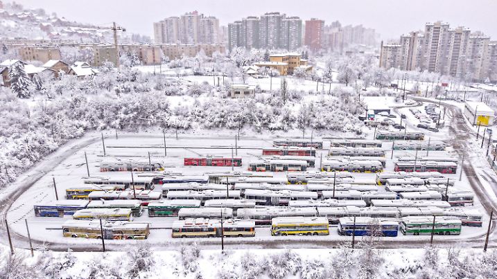 24.12.2024, Bosnien-Herzegowina, Sarajevo: Luftaufnahme bei starkem Schneefall auf Oberleitungsbusse auf einem Parkplatz in Sarajevo, Bosnien. Foto: Armin Durgut/AP/dpa +++ dpa-Bildfunk +++