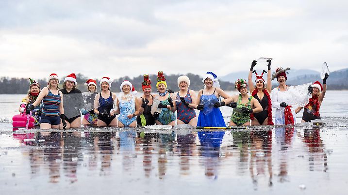 13.12.2024, Großbritannien, Kingussie: Mitglieder der Eisbader-Gruppe "Loch Insh Dippers" nehmen an einem Weihnachtsschwimmen im zugefrorenen Loch Insh, Kingussie, teil. Foto: Jane Barlow/PA Wire/dpa +++ dpa-Bildfunk +++