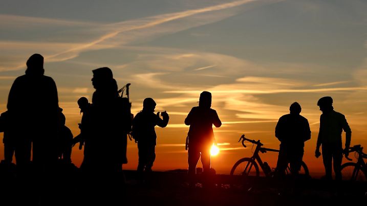 29.12.2024, Sachsen-Anhalt, Schierke: Wanderer stehen bei Sonnenaufgang auf dem Brockenplateau. Derzeit herrscht im Harz eine Inversionswetterlage. Während in den tieferen Harzlagen kalte Luftschichten für Temperaturen unter Null Grad Celsius sorgen, liegen die Temperaturen in den Hochlagen des Harzes im Plusbereich. Foto: Matthias Bein/dpa +++ dpa-Bildfunk +++