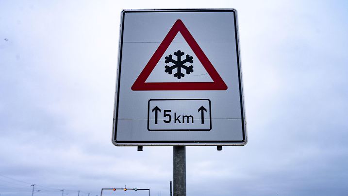 01.04.2023, Mecklenburg-Vorpommern, Altefähr: Ein Verkehrsschild warnt vor der Rügenbrücke, einer Straßenverbindung zur Insel Rügen, vor Glatteis. Foto: Stefan Sauer/dpa +++ dpa-Bildfunk +++