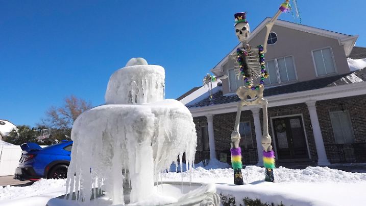 An ice covered fountain sits in front of a Mardi Gras festooned skeleton the day after a rare and record setting snowstorm in River Ridge, La., a suburb of New Orleans, Wednesday, Jan. 22, 2025. (AP Photo/Gerald Herbert)
