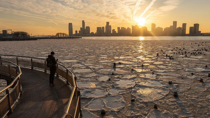 23.01.2025, USA, New York: Eine Person macht ein Foto vom Hudson River, der von Eis bedeckt ist. Foto: Yuki Iwamura/AP/dpa +++ dpa-Bildfunk +++