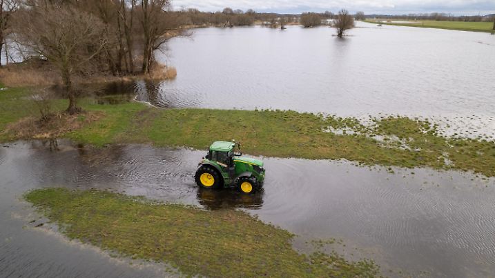 ARCHIV - 22.02.2024, Brandenburg, Schmergow: Landwirt Peter de Vries fährt mit seinem Traktor über seine überfluteten Felder. (Luftaufnahme mit einer Drohne) (zu dpa: «Versicherer: 14 000 Adressen in Brandenburg von Hochwasser bedroht») Foto: Georg Moritz/dpa +++ dpa-Bildfunk +++