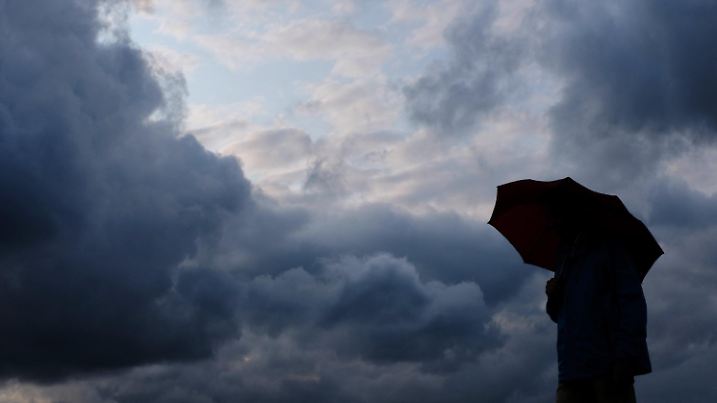 ARCHIV - 12.07.2019, Nordrhein-Westfalen, Duisburg: Ein Mann geht mit einem Regenschirm vor aufziehenden dunklen Wolken spazieren. (zu dpa: «Regnerisches und stürmisches Wetter in Hessen») Foto: Martin Gerten/dpa +++ dpa-Bildfunk +++