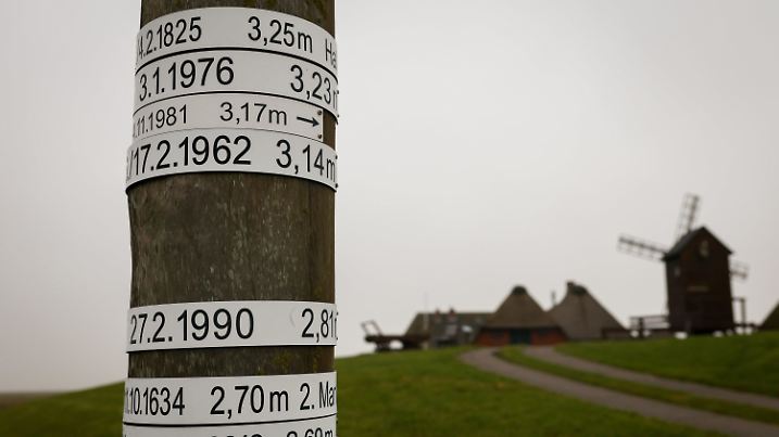 PRODUKTION - 21.01.2025, Schleswig-Holstein, Langeneß: Ein Pegelstand mit den Sturmfluten der vergangenen Jahrhunderte steht vor der Ketelswarft auf der Hallig Langeneß. Die große Sturmflut vor 200 Jahren, vom 3. auf den 4. Februar 1825, gilt als eine der vermutlich schwersten Sturmfluten der letzten Jahrhunderte. (zu dpa: «Von den Fluten weggerissen») Foto: Christian Charisius/dpa +++ dpa-Bildfunk +++
