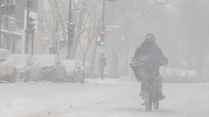 06.02.2025, Kanada, Montreal: Ein Radfahrer fährt bei Schneefall in der Innenstadt von Montreal. Foto: Christinne Muschi/The Canadian Press/AP/dpa +++ dpa-Bildfunk +++