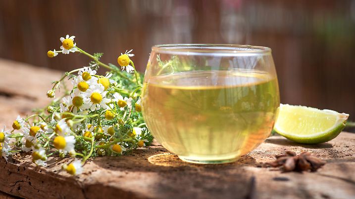 Cup of tea with chamomile flower on a wooden table. Organic, natural drink and glass cup on wooden table. Organic, natural drink and glass cup