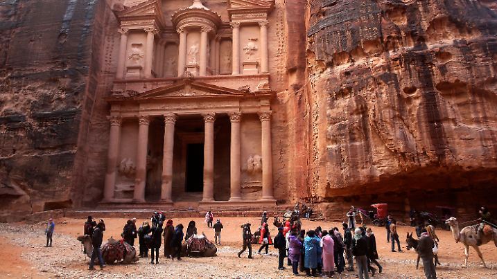 ARCHIV - 13.02.2017, Jordanien, Petra: Touristen stehen mit Plastikponchos im Regen vor dem sogenannten "Schatzhaus", Jordaniens berühmtestem archäologischen Denkmal, das von der nabatäischen Zivilisation im archäologischen Park Petra des Königreichs übrig geblieben ist. (zu "Besucher müssen wegen Regens jordanische Felsenstadt Petra verlassen" vom 09.11.2018) Foto: Sam Mcneil/AP/dpa +++ dpa-Bildfunk +++