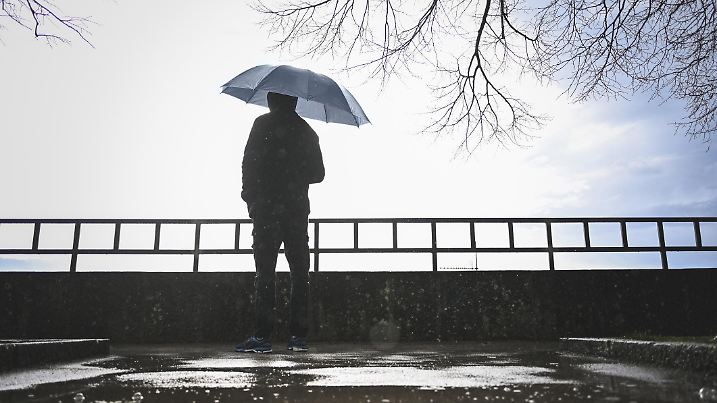 rear view portrait of a man standing under the rain and looking away.