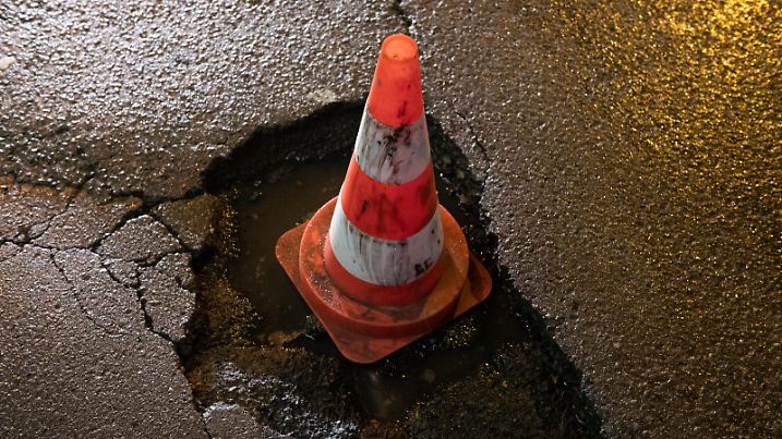 11.01.2019, Berlin: Ein großes und tiefes Schlagloch am Checkpoint Charlie sorgt für Ärger bei Rad- und Autofahrern. Seit geraumer Zeit zwingt das Loch zum Abbremsen. Anstatt den Schaden umgehend zu beheben, wurde nur ein Pylon in das Loch gestellt. Foto: Paul Zinken/dpa