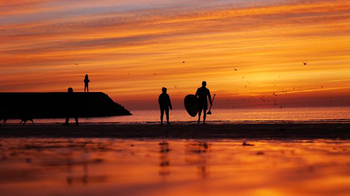 01.03.2025, Großbritannien, Cullercoats Bay: Paddelboarder gehen vor Sonnenaufgang in die Nordsee bei Cullercoats Bay. Für den März wird ein milder Start erwartet. Der Himmel soll sich aufhellen und in einigen Gebieten werden Temperaturen bis zu 14 Grad erwartet. Foto: Owen Humphreys/PA Wire/dpa +++ dpa-Bildfunk +++