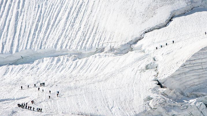ARCHIV - 21.07.2015, Schweiz, Saas-Fee: Bergsteiger beim Überqueren eines Gletschers mit Eis und Schnee auf dem Weg zum Allalinhorn. (zu dpa: «Snowboardfahrer stürzt in Gletscherspalte») Foto: Dominic Steinmann/dpa +++ dpa-Bildfunk +++