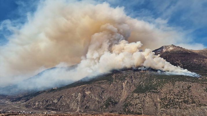 HANDOUT - 06.03.2025, Italien, Latsch: Eine mächtige Qualmwolke steht wegen eines großen Waldbrand über dem Sonnenberg im Südtiroler Vinschgau. Rund 250 Einsatzkräfte waren mit Löscharbeiten beschäftigt. Ursache des Feuers war offenbar ein in Brand geratener Pkw. Foto: LPA/Landesfeuerwehrverband/APA/dpa - ACHTUNG: Nur zur redaktionellen Verwendung im Zusammenhang mit der aktuellen Berichterstattung und nur mit vollständiger Nennung des vorstehenden Credits +++ dpa-Bildfunk +++