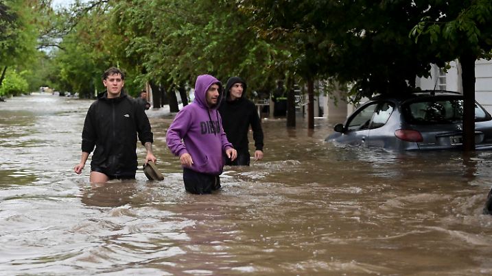 07.03.2025, Argentinien, Bahia Blanca: Menschen waten durch eine überschwemmte Straße nach einem Unwetter in Bahia Blanca. Foto: Juan Sebastian Lobos/AP/dpa +++ dpa-Bildfunk +++