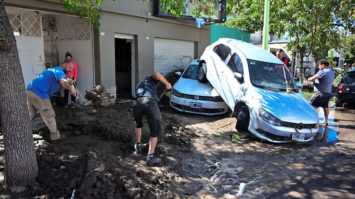 People work to clean a street next to damaged cars after a flooding struck the city of Bahia Blanca, in the province of Buenos Aires, Argentina March 8, 2025. REUTERS/Juan Sebastian Lobos