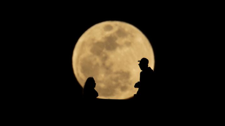 13.03.2025, USA, Los Angeles: Menschen heben sich vom aufgehenden Vollmond am Abendhimmel ab. Der Blutmond wird später in der Nacht auftreten, wenn eine totale Mondfinsternis dem Mond eine rötliche Färbung verleiht. Foto: Ringo Chiu/ZUMA Press Wire/dpa +++ dpa-Bildfunk +++