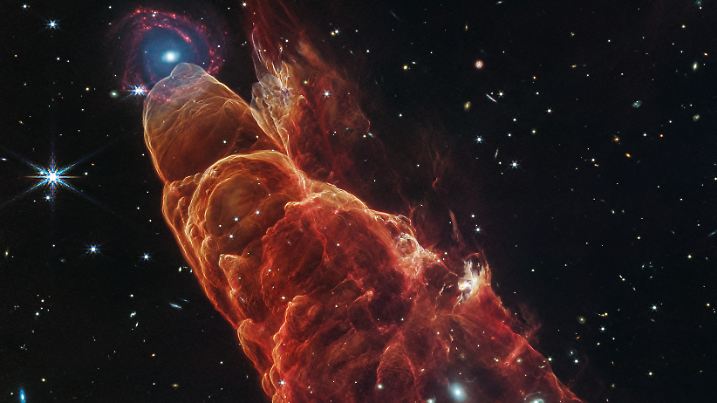 Am oberen Bildrand leuchtet eine ferne Spiralgalaxie – ein kosmischer Zufall mit beeindruckender Tiefenwirkung.