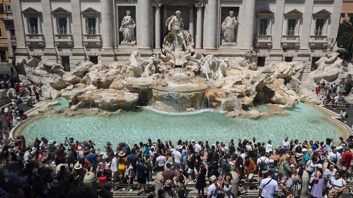 Touristen am Trevi Brunnen in Rom - eine Erleichterung von der Hitze in Italien gibt es hier trotz des verlockenden Wassers nicht.