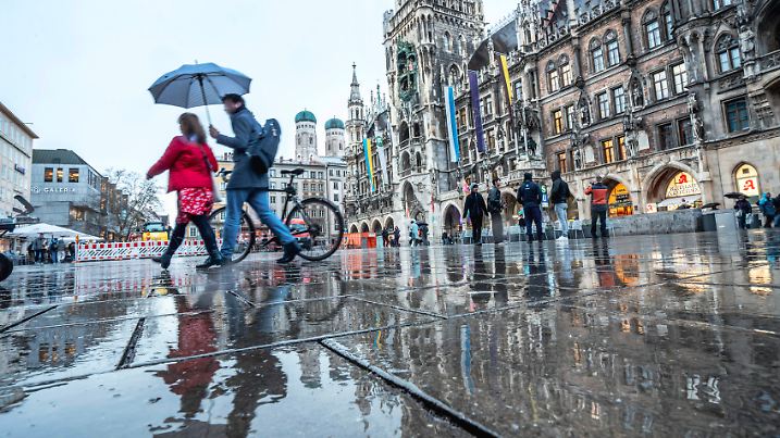 Wolkenbruch und Gewitter, Passanten eilen mit Regenschirm über den leeren Marienplatz, München, März 2025