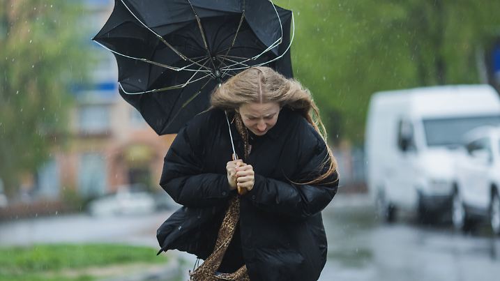 Frau hält Regenschirm bei Sturm und Regen