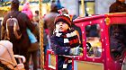 Funny little kid boy on a carousel at Christmas funfair or market, outdoors. Happy child having fun. Traditional xmas market in Germany, Europe. Holiday, children, lifestyle concept.