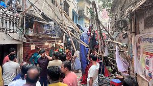 Residents stand in an alley after vacating their house next to a fallen scaffolding following an earthquake in Dhaka
