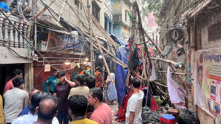 Residents stand in an alley after vacating their house next to a fallen scaffolding following an earthquake in Dhaka
