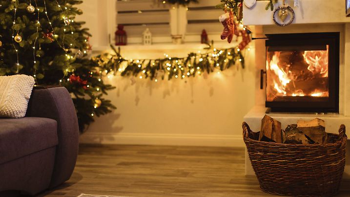 Weihnachtsbaum steht in einem Wohnzimmer, mit Abstand zum Kamin