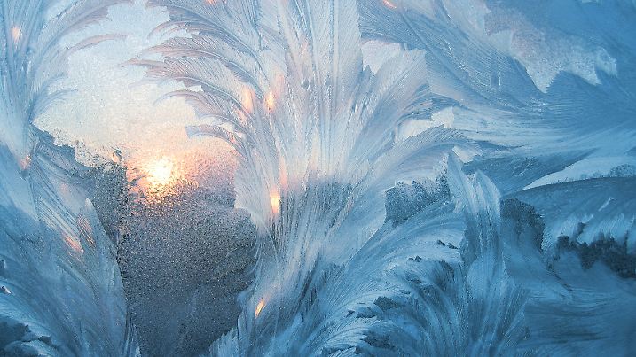 Gefrorene Scheibe bei Kälte mit Eis im Winter mit Sonnenschein im Hintergrund