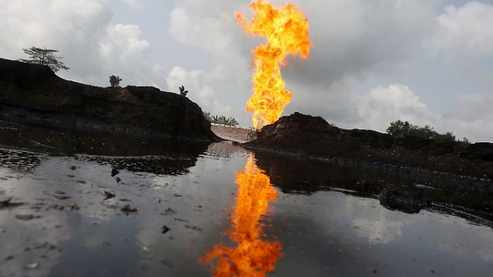 FILE PHOTO: A reflection of gas flaring is seen in the pool of oil-smeared water at a flow station in Ughelli, Delta State