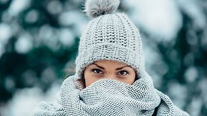 Portrait of a beautiful young woman wearing scarf and a a hat on a cold winter day during snow