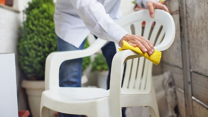 Mann reinigt weißen Kunststoffstuhl